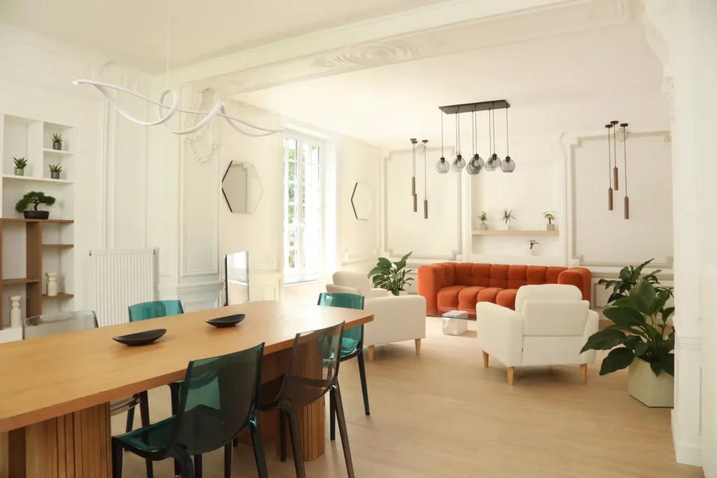 Rénovation d'un T5 de caractère à Chantilly par Ilot Archi : vaste pièce de vie avec moulures, canapé terracotta et table à manger en bois.