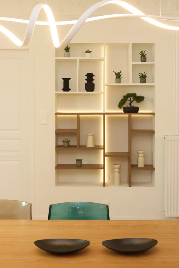 Niche murale sur mesure avec rétroéclairage LED et étagères en bois créée par Ilot Archi dans un appartement à Chantilly.