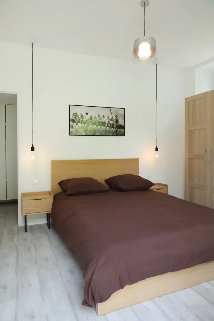 Agencement de chambre par Ilot Archi : lit double moderne en bois clair et parquet blanchi dans un T2 à Chantilly.