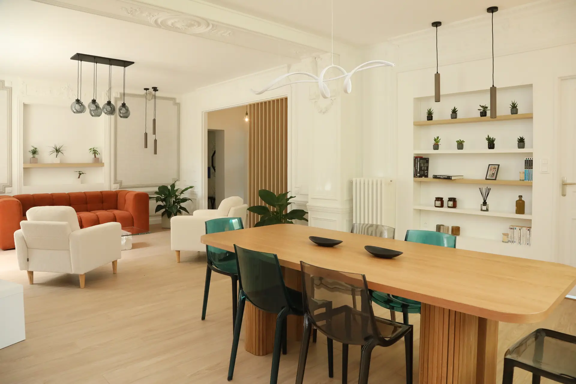 Espace repas sur mesure conçu par Ilot Archi à Chantilly avec chaises design, suspensions modernes et étagères encastrées rétroéclairées.