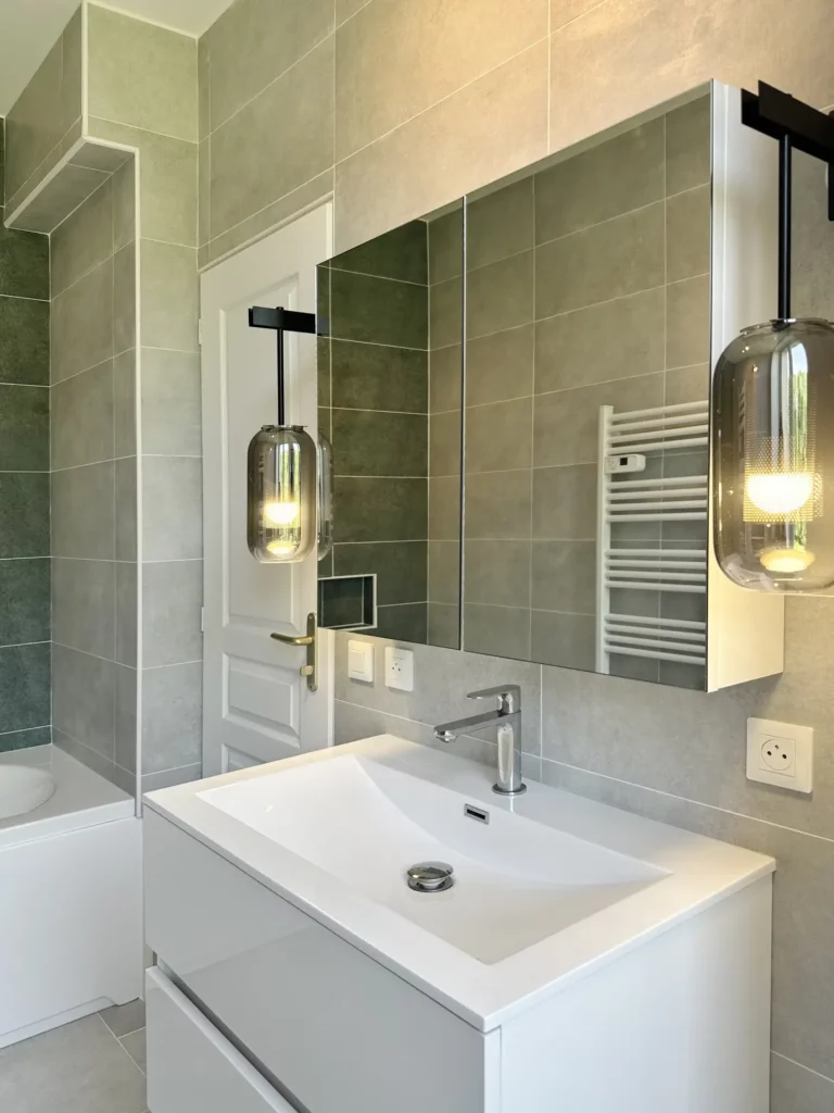 Meuble vasque moderne blanc et suspensions en verre fumé installés par Ilot Archi dans une salle de bains à Chantilly.